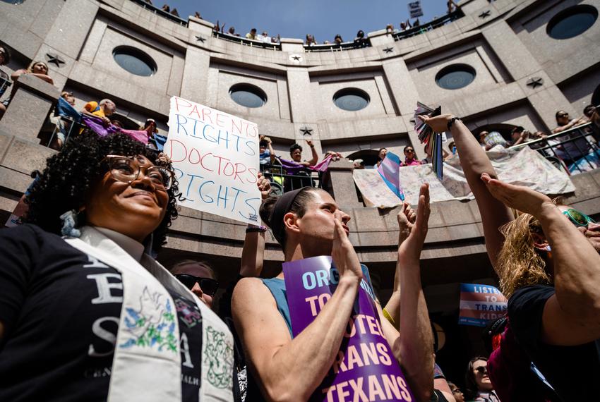 People line the railing on all three levels of the outdoor rotunda of the state Capitol in Austin, and wave signs during the "Fight for our Lives" rally in opposition of anti-LGBTQ+ bills on March 27, 2023.
