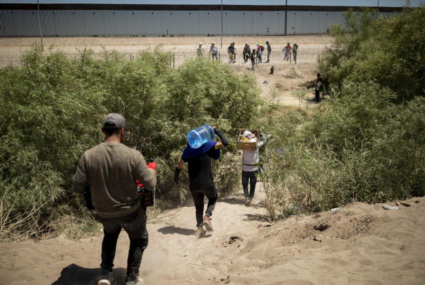 Migrants carry supplies before crossing the Rio Grande River and into the U.S. from Mexico on Monday, May 8, 2023, in Juárez, Chihuahua. Several hundred migrants have been waiting on the U.S. side of the river to be picked up and processed by CBP.