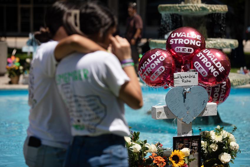 Destiny Esquivel, a cousin of Maite Rodriguez, embraces another family member beside the memorial cross for Lexi Rubio in the city plaza on the one year mark of the Robb Elementary school shooting in Uvalde on May 24, 2023.