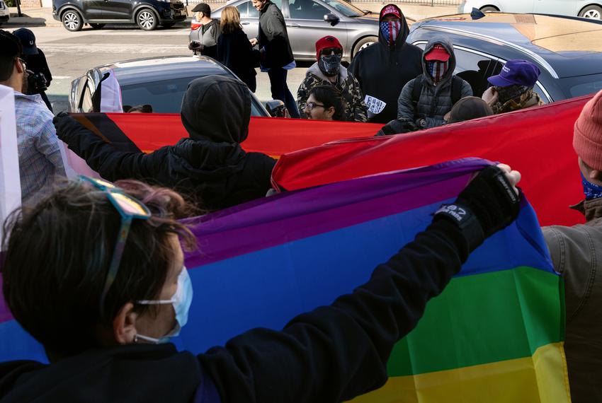 Counter-protesters form a barricade outside of a transgender storytelling event in Denton, TX on November 19, 2022. A wall of people holding LGBTQ flags kept protestors against the event at a distance as the books were read to kids and adults indoors.
