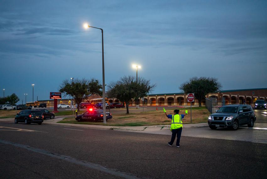 A woman directs traffic as students are dropped off at  Muller Elementary, which could be at extreme risk due to ethylene oxide emissions from the Midwest plant in Laredo, Texas. Juan Jose “JJ” Nevares attended the school a year before he was diagnosed with cancer.