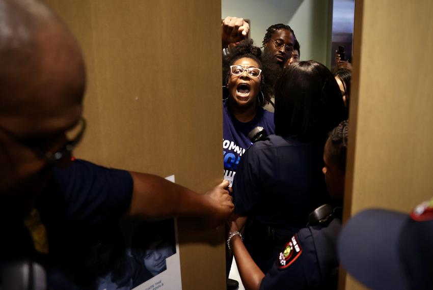 Kourtney Revels, at center, the mother of a third-grade student at Houston ISD's Elmore Elementary School, confronts district staff limiting public access to a school board meeting Thursday at HISD headquarters in northwest Houston. (Annie Mulligan for Houston Landing)