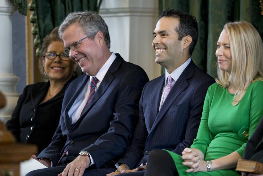 Jeb Bush puts his hand on his son George P. Bush's knee during a light moment in the younger Bush's swearing-in ceremony on Jan. 2, 2015, as Texas land commissioner. At right is George P. Bush's wife, Amanda Bush.