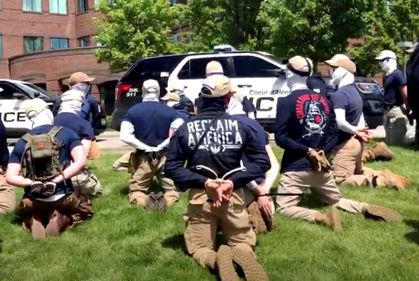 Police officers, some in riot gear, guard a group of men, who police say are among 31 arrested for conspiracy to riot, in Coeur d'Alene, Idaho on June 11, 2022. The men, found in the rear of a U Haul van in the vicinity of a Pride event, are affiliated with the Patriot Front group.