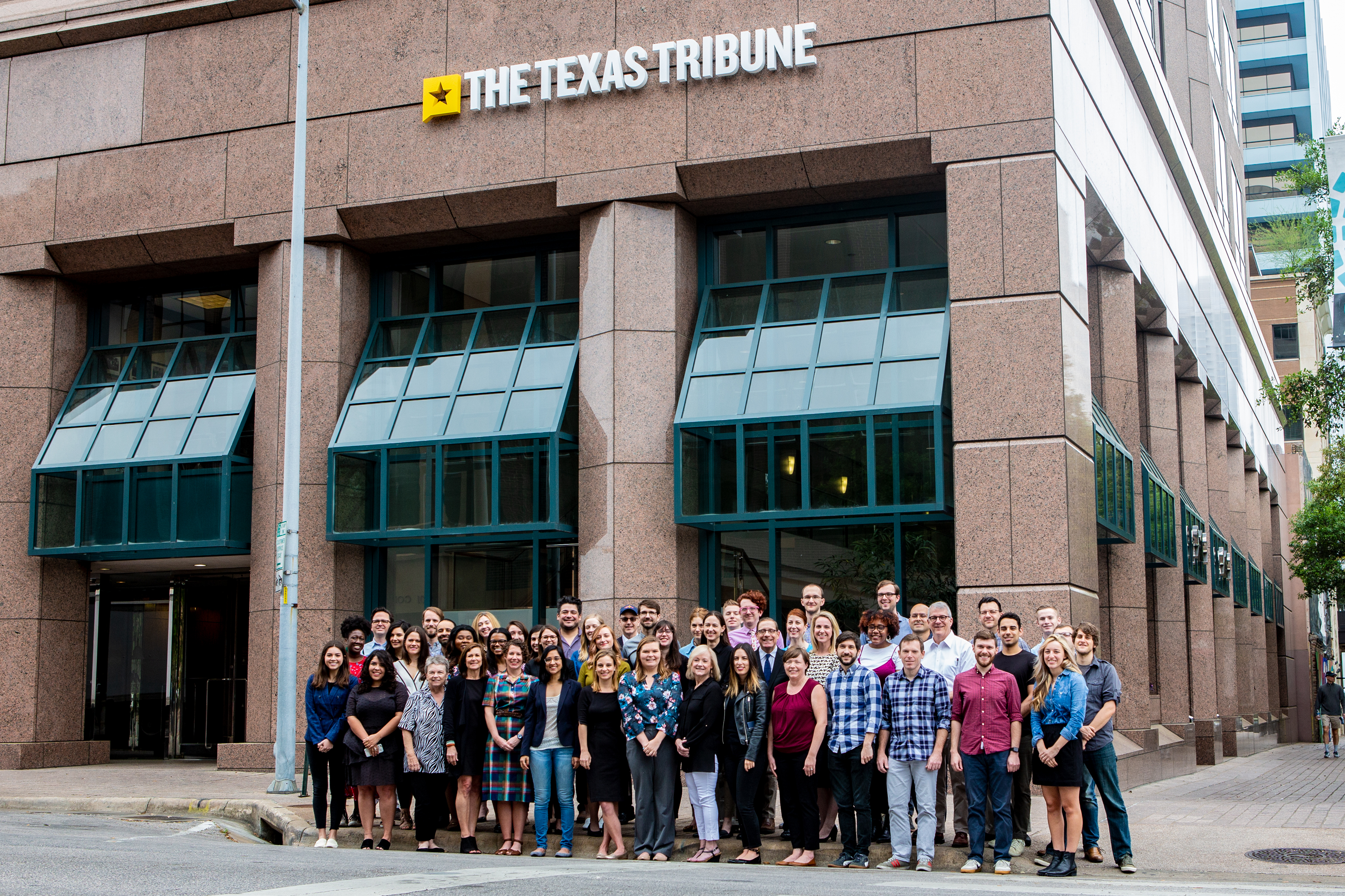 Members of the Texas Tribune staff stand together in front their headquarters.